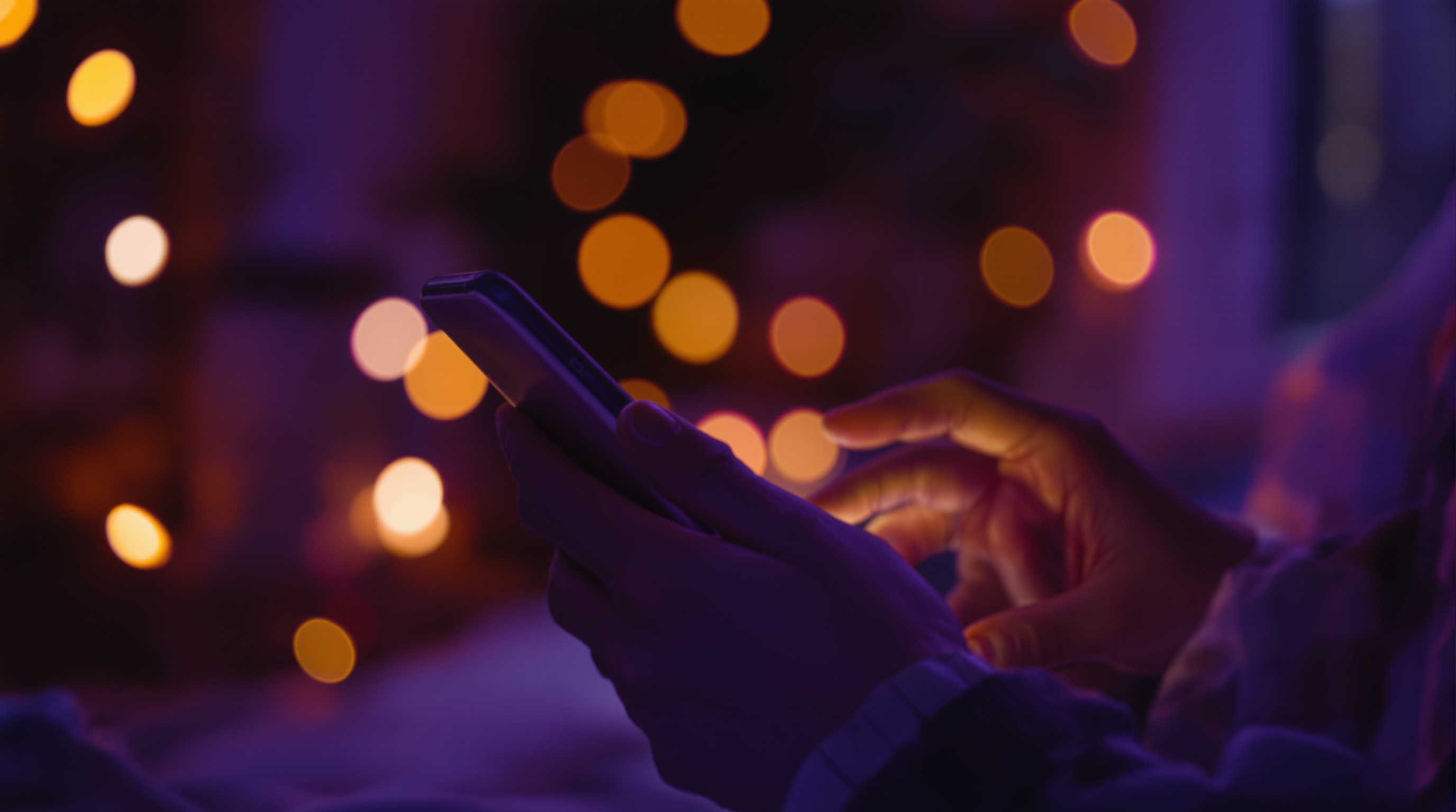 Hands holding a phone starting a new chat in a cozy room lit by warm bokeh at dusk